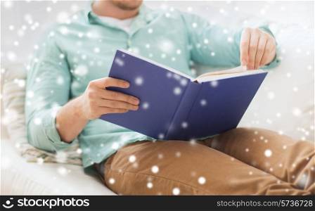 leisure, education, literature and people concept - close up of man and sitting or lying on couch and reading book at home