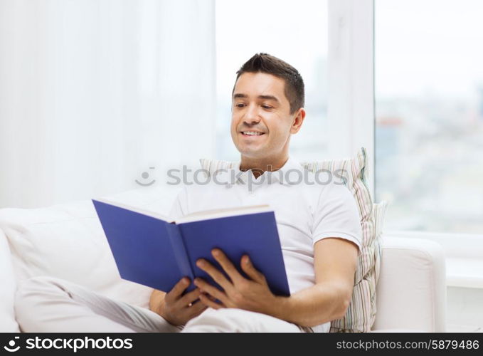 leisure, education, literature and people concept - happy man reading book at home