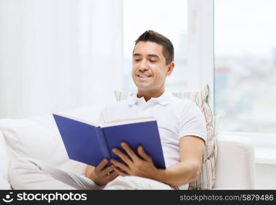 leisure, education, literature and people concept - happy man reading book at home