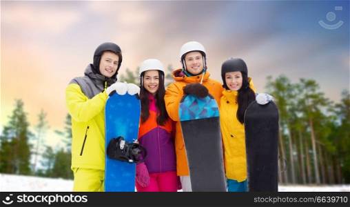 leisure, extreme sport and friendship concept - happy friends in helmets with snowboards outdoors in winter over natural background. happy friends in helmets with snowboards outdoors