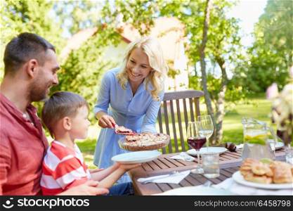 leisure, family and people concept - happy mother, father and little son eating pie at festive dinner or summer garden party. happy family eating pie at summer garden party