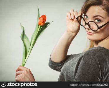 Leisure feelings flora nature beauty feminine concept. Seducive nerdy girl holding tulip. Young blonde lady with red flower.. Seducive nerdy girl holding tulip.