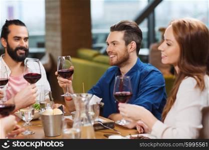 leisure, food and drinks, celebration people and holidays concept - smiling friends having dinner and drinking red wine at restaurant
