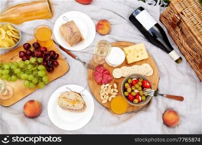 leisure, food and drinks concept - close up of snack and picnic basket on blanket. food, drinks and picnic basket on blanket