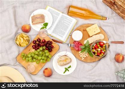 leisure, food and drinks concept - close up of snacks and picnic basket on blanket on grass at summer park. food, drinks and picnic basket on blanket on grass