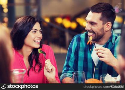 leisure, food and drinks, people and holidays concept - happy couple with friends having dinner at restaurant. happy friends having dinner at restaurant. happy friends having dinner at restaurant
