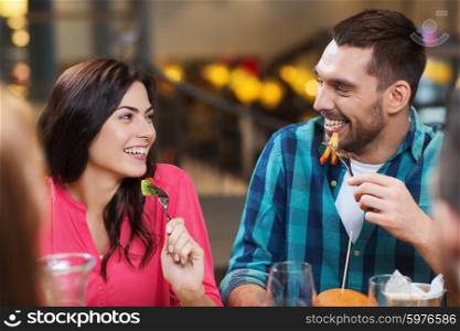 leisure, food and drinks, people and holidays concept - happy couple with friends having dinner at restaurant