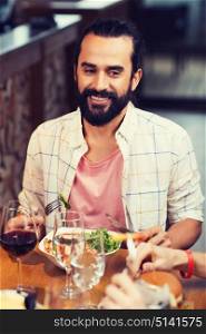 leisure, food and drinks, people and holidays concept - happy man with friends having dinner at restaurant. happy man having dinner at restaurant