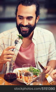 leisure, food and drinks, people and holidays concept - happy man with friends having dinner at restaurant. happy man having dinner at restaurant