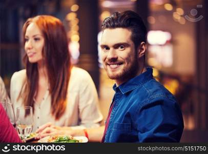 leisure, food and drinks, people and holidays concept - happy man with friends having dinner at restaurant. happy man with friends having dinner at restaurant