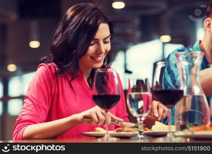 leisure, food and drinks, people and holidays concept - happy woman with friends having dinner at restaurant. happy woman having dinner at restaurant