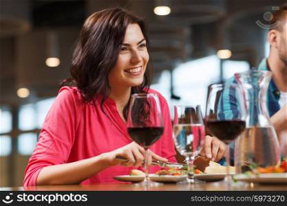 leisure, food and drinks, people and holidays concept - happy woman with friends having dinner at restaurant