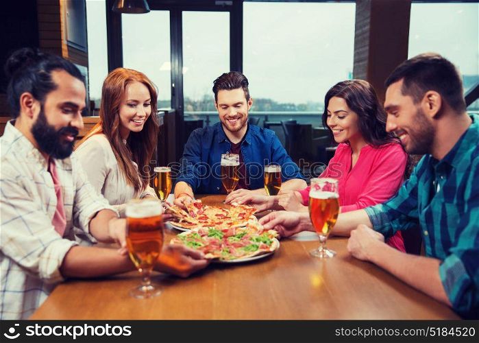 leisure, food and drinks, people and holidays concept - smiling friends eating pizza and drinking beer at restaurant or pub. friends eating pizza with beer at restaurant