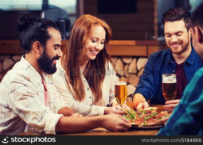 leisure, food and drinks, people and holidays concept - smiling friends eating pizza and drinking beer at restaurant or pizzeria. friends sharing pizza with beer at pizzeria