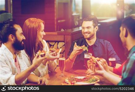 leisure, food and drinks, people and holidays concept - smiling friends eating pizza and drinking beer at restaurant or pub. friends eating pizza with beer at restaurant