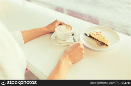 leisure, food and drinks, people and lifestyle concept - close up of young woman hands eating cake and drinking coffee at cafe
