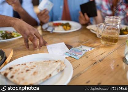 leisure, food and payment concept - male hand with bill and money or tips on restaurant table. male hand with bill and money on restaurant table