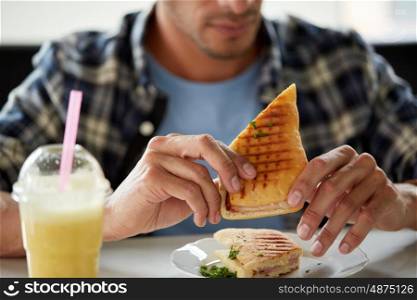 leisure, food and people concept - close up of man eating sandwich at cafe for lunch
