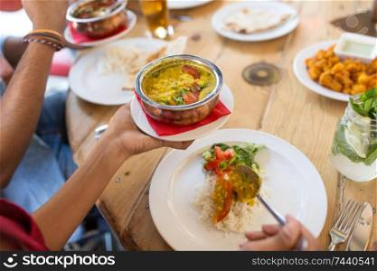 leisure, food and people concept - close up of woman eating with friends at restaurant. woman eating with friends at restaurant