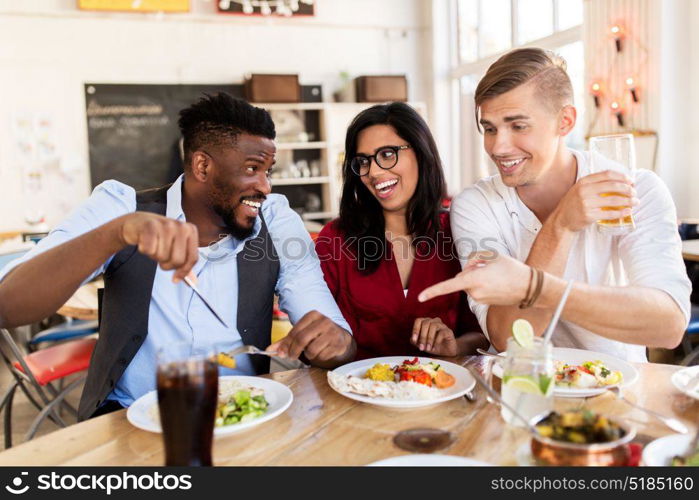 leisure, food and people concept - group of happy international friends eating and having fun at restaurant table. happy friends eating and having fun at restaurant