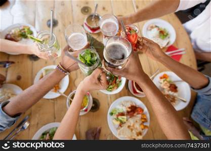 leisure, food and people concept - group of happy international friends eating and clinking glasses at restaurant table. friends eating and clinking glasses at restaurant