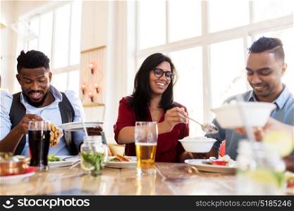 leisure, food and people concept - group of happy international friends eating at restaurant table. happy friends eating at restaurant