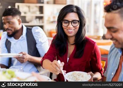 leisure, food and people concept - group of happy international friends eating at restaurant table. happy friends eating at restaurant