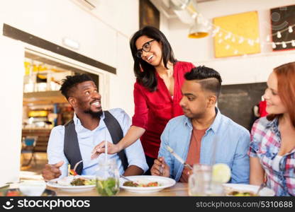 leisure, food and people concept - group of happy international friends eating at restaurant table. happy friends eating at restaurant