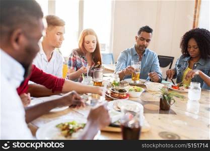 leisure, food and people concept - group of international friends eating at restaurant table. friends eating at restaurant