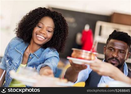 leisure, food and people concept - happy african american couple eating at restaurant. happy african american couple eating at restaurant