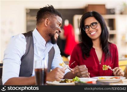 leisure, food and people concept - happy couple eating at restaurant. happy couple eating at restaurant