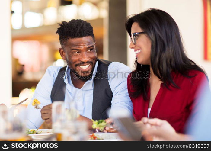 leisure, food and people concept - happy couple eating at restaurant. happy couple eating at restaurant