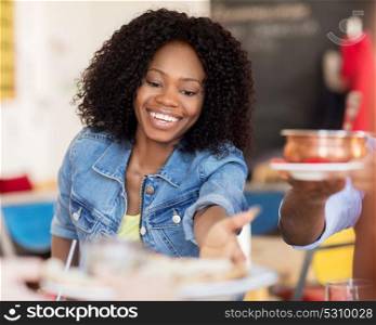 leisure, food and people concept - happy woman with friends eating at restaurant. happy woman with friends eating at restaurant