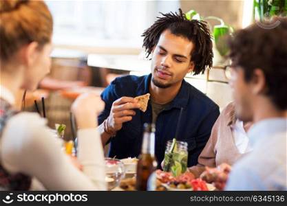 leisure, food and people concept - man with friends eating at restaurant. man with friends eating at restaurant