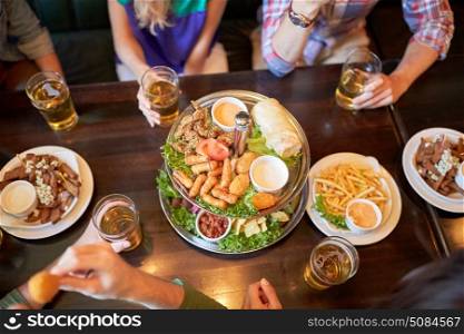 leisure, food, drinks, people and holidays concept - friends eating snack and drinking beer at bar or pub. friends eating and drinking at bar or pub. friends eating and drinking at bar or pub