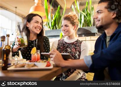 leisure, food, drinks, people and holidays concept - happy friends eating and drinking at bar or cafe. happy friends eating and drinking at bar or cafe