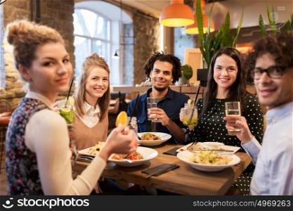 leisure, food, drinks, people and holidays concept - happy friends eating and drinking at restaurant. happy friends eating and drinking at restaurant
