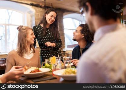 leisure, food, drinks, people and holidays concept - happy friends eating and drinking at restaurant. happy friends eating and drinking at restaurant