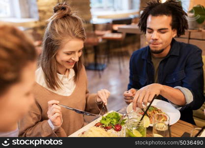 leisure, food, drinks, people and holidays concept - happy friends eating and drinking at restaurant. happy friends eating and drinking at restaurant