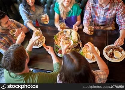 leisure, food, drinks, people and holidays concept - happy friends eating snack and drinking beer at bar or pub. happy friends eating and drinking at bar or pub
