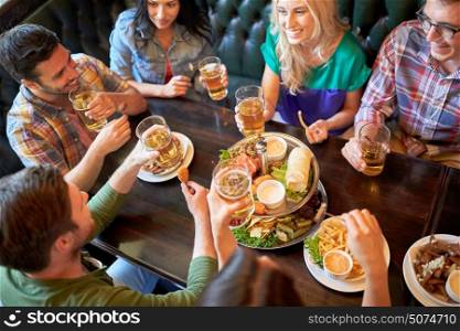 leisure, food, drinks, people and holidays concept - happy friends eating snack and drinking beer at bar or pub. happy friends eating and drinking at bar or pub