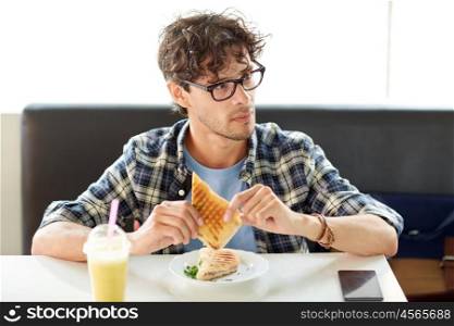 leisure, food, eating and people concept - happy man eating sandwich at cafe for lunch