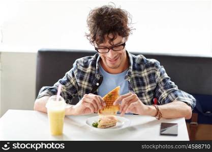 leisure, food, eating and people concept - happy man eating sandwich at cafe for lunch