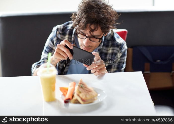 leisure, food, eating and people concept - man with smartphone photographing his lunch at cafe