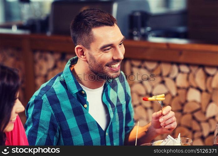 leisure, food, eating, people and holidays concept - happy man with friends having dinner at restaurant. happy man having dinner at restaurant