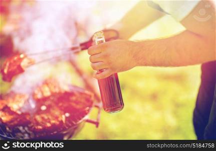 leisure, food, people and holidays concept - man cooking meat on barbecue grill at outdoor summer party. man cooking meat on barbecue grill at summer party
