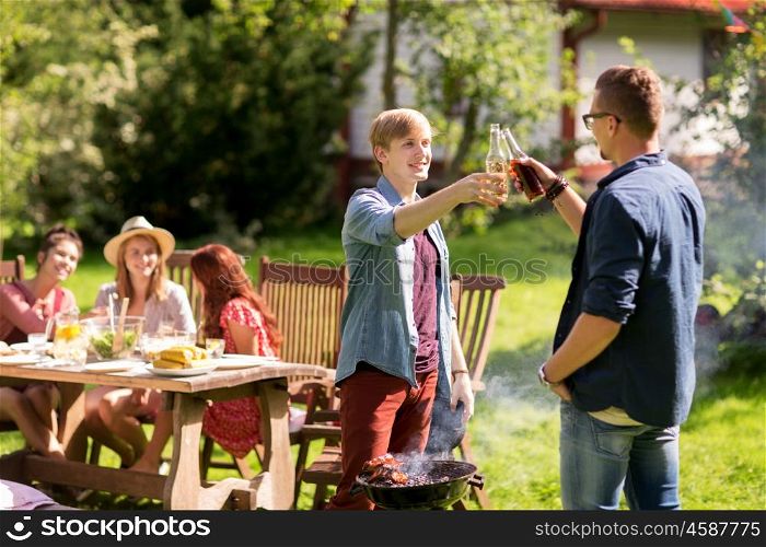 leisure, food, people, friendship and holidays concept - happy friends cooking meat on barbecue grill and drinking beer at summer outdoor party