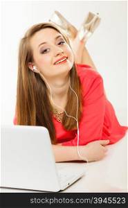 Leisure free time, music, online and internet concept - happy teenage girl with earphones and laptop computer
