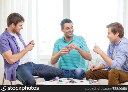 leisure, games and lifestyle concept - happy three male friends playing poker at home