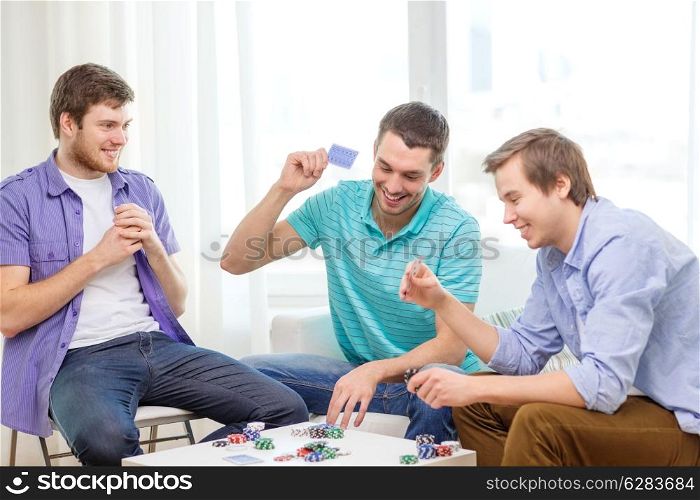 leisure, games and lifestyle concept - happy three male friends playing poker at home